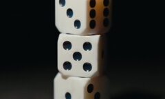 Three white dice stacked against a dark background.